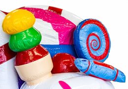 Kryty, wielozadaniowy dmuchany zamek w krainie cukierków o wyjątkowym designie z dwoma wejściami, zjeżdżalnią pośrodku i obiektami 3D dla dzieci. Kup dmuchane zamki online w JB Dmuchańce Polska